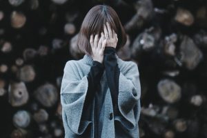 Woman Covering Face With Hands Against Wall