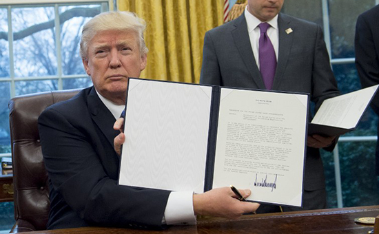 US President Donald Trump holds up an executive order withdrawing the US from the Trans-Pacific Partnership after signing it alongside White House Chief of Staff Reince Priebus (R) in the Oval Office of the White House in Washington, DC, January 23, 2017. Trump the decree Monday that effectively ends US participation in a sweeping trans-Pacific free trade agreement negotiated under former president Barack Obama. / AFP PHOTO / SAUL LOEB