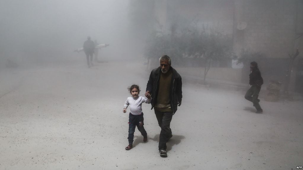 A Syrian man and girl flee following a reported government air strike on the rebel-controlled town of Hamouria, in the eastern Ghouta region on the outskirts of the capital Damascus, on April 4, 2017. / AFP PHOTO / ABDULMONAM EASSA